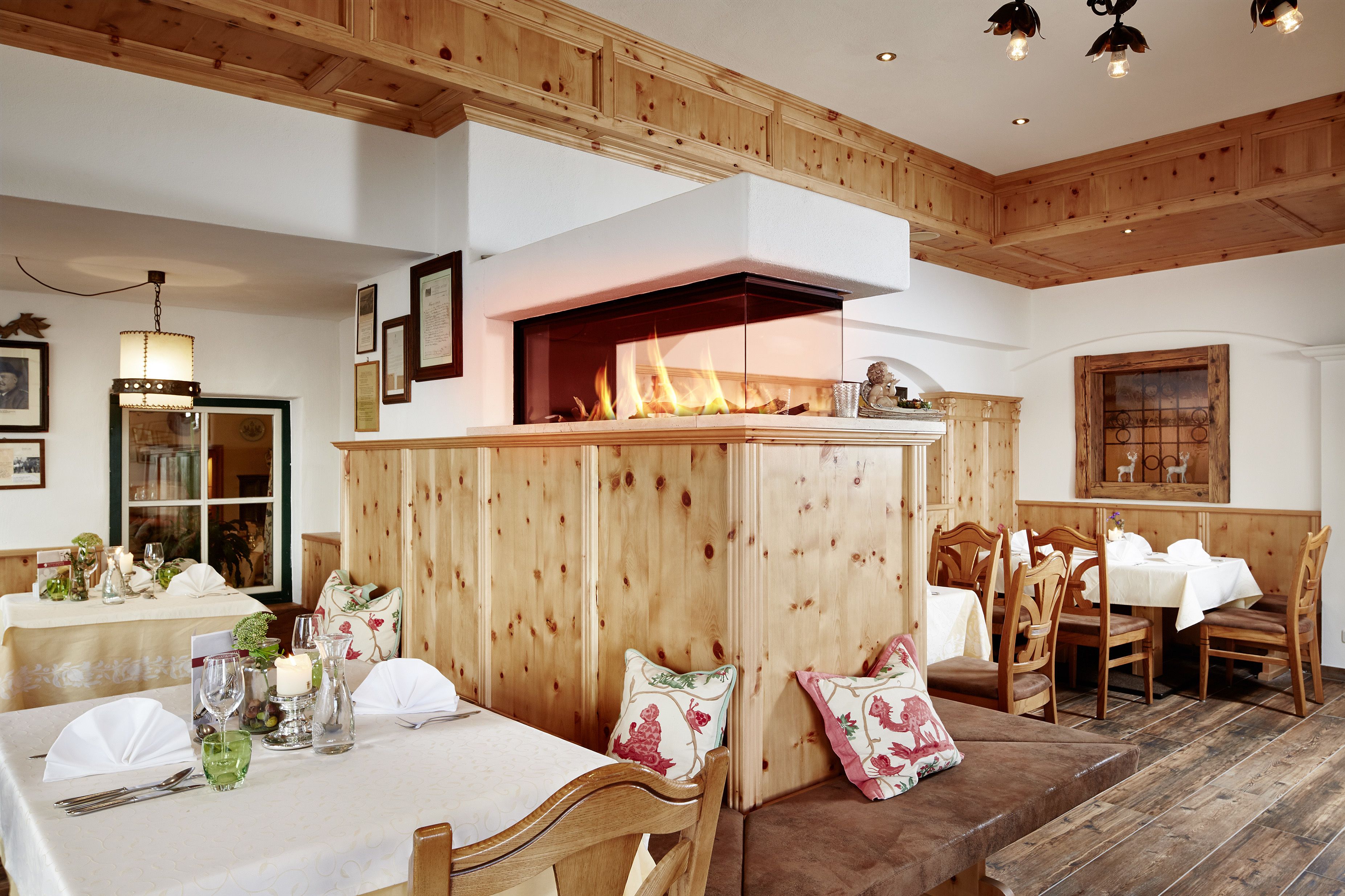 A cozy dining area with wooden paneling, a fireplace, and a table set for a meal.