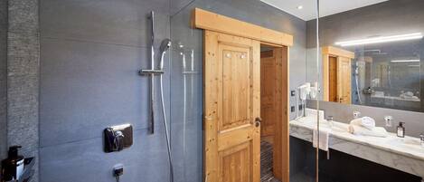 Un baño moderno con ducha, puerta de madera y tocador con espejo.