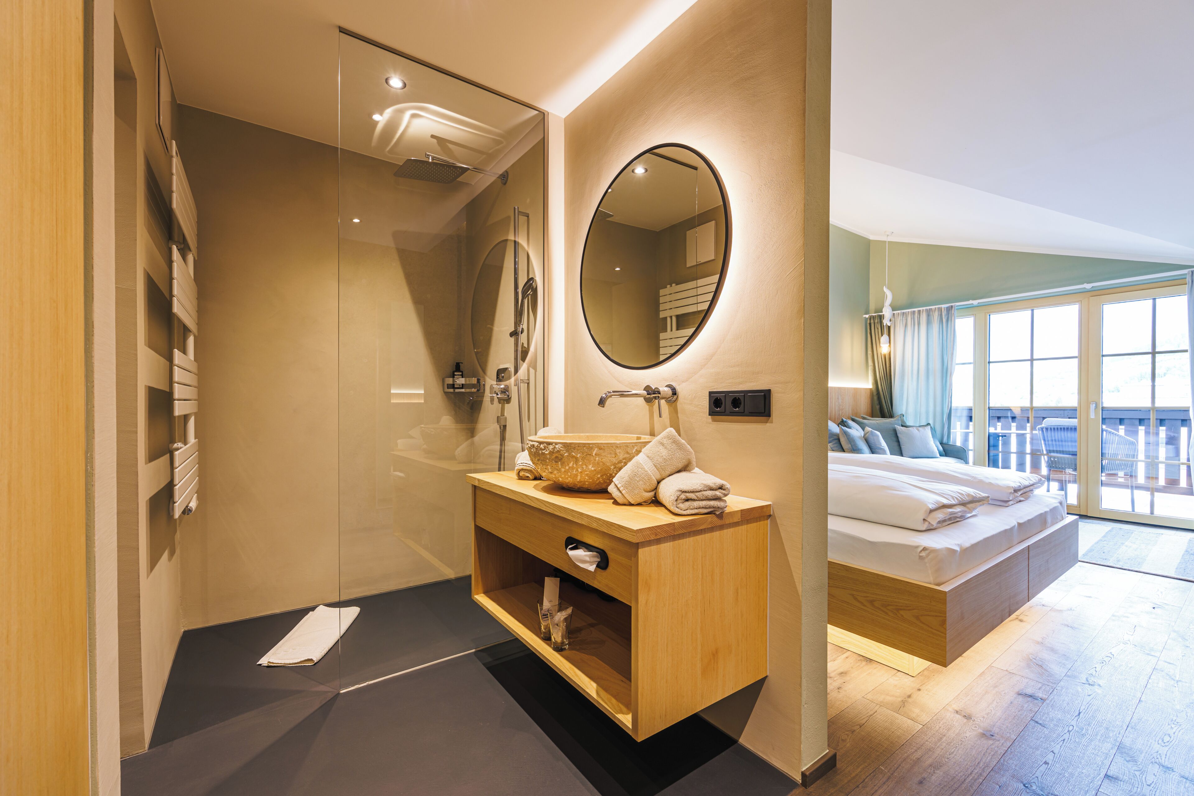 A modern bathroom with a glass shower enclosure, a wooden vanity with a bowl sink, and a large mirror.