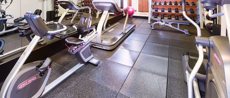 A gym with treadmills, ellipticals, and a rack of dumbbells.