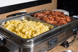 A buffet with scrambled eggs and bacon.