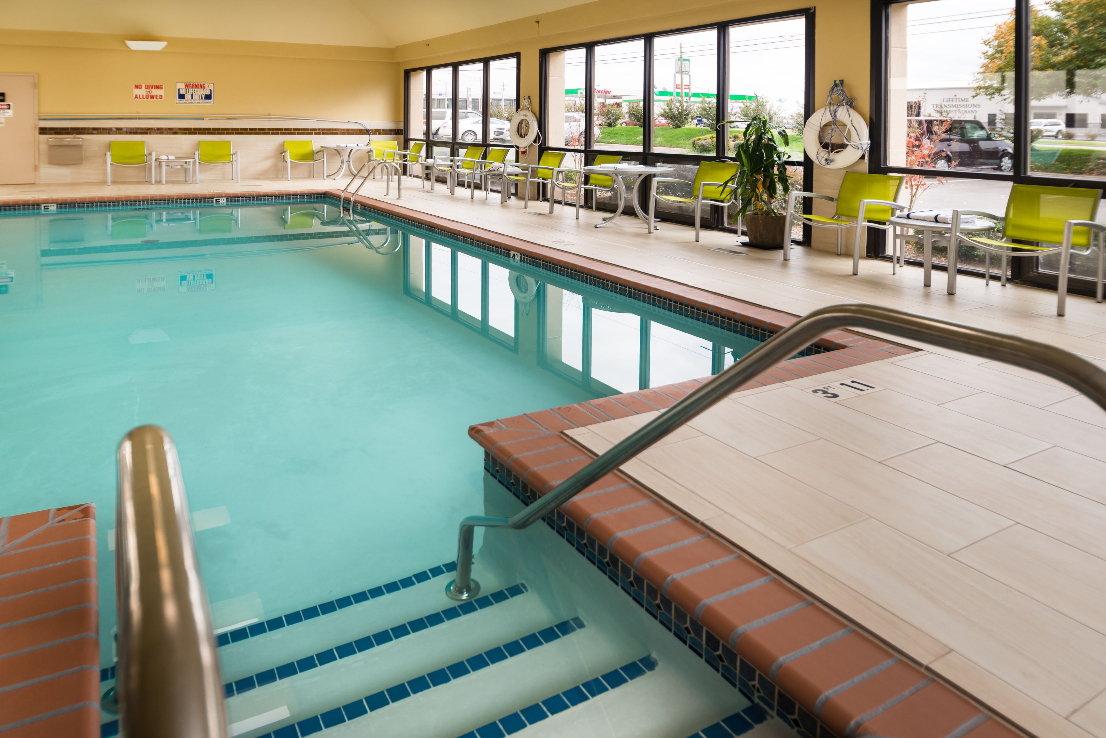 A swimming pool with a tiled deck, chairs, and a lifeguard stand.