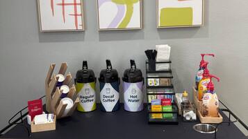 A coffee station with dispensers labeled 'Regular Coffee,' 'Decaf Coffee,' and 'Hot Water,' along with a coffee machine and a bottle of coffee-mate.