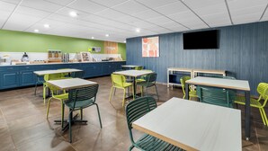 A modern restaurant with green and yellow chairs, white tables, and a blue accent wall.