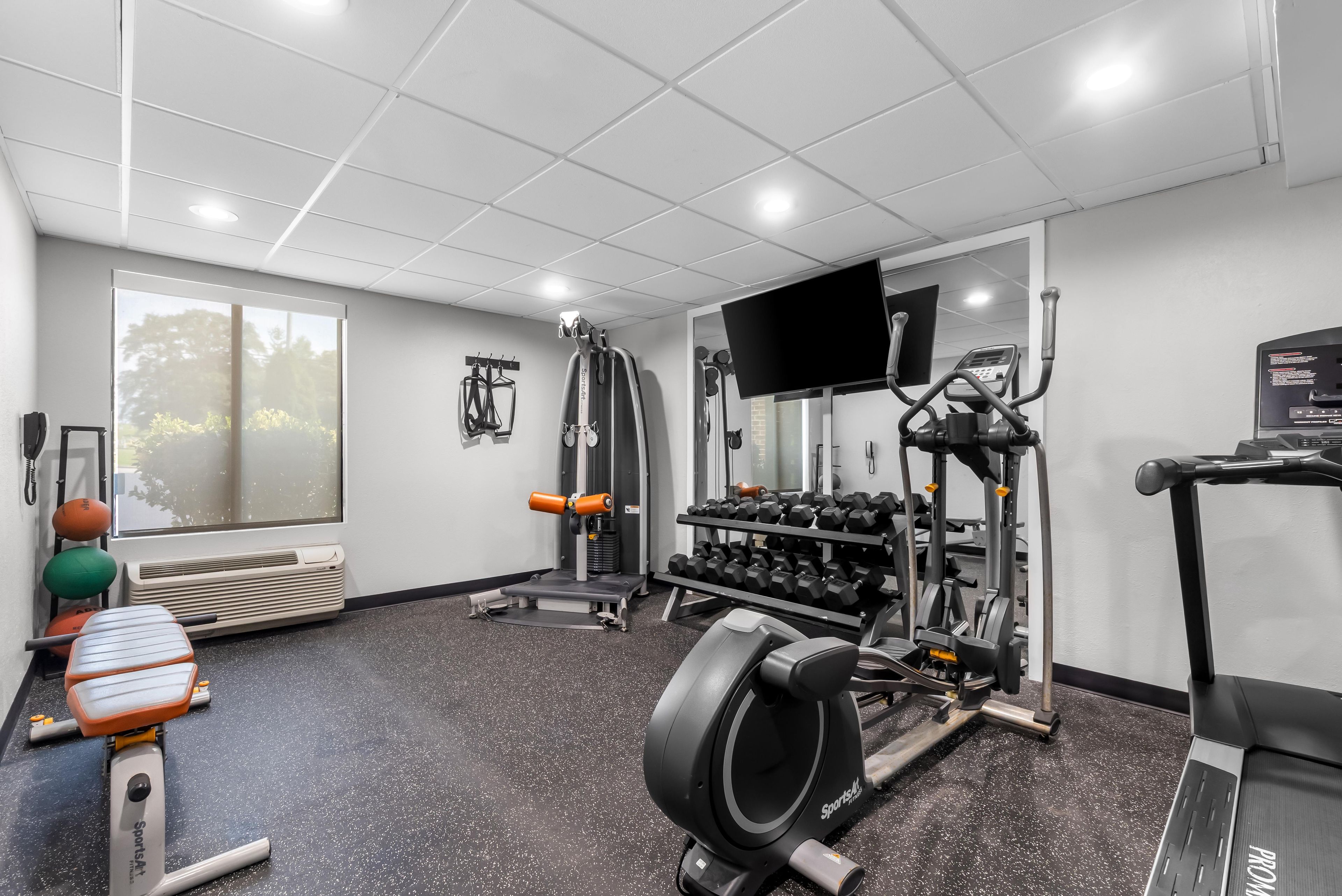 A gym with various exercise equipment, a large window, and a flat-screen TV.