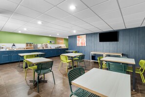 A modern cafe interior with multiple tables and chairs, a coffee machine, and a menu board. - Spark by Hilton Kimball (Jasper)