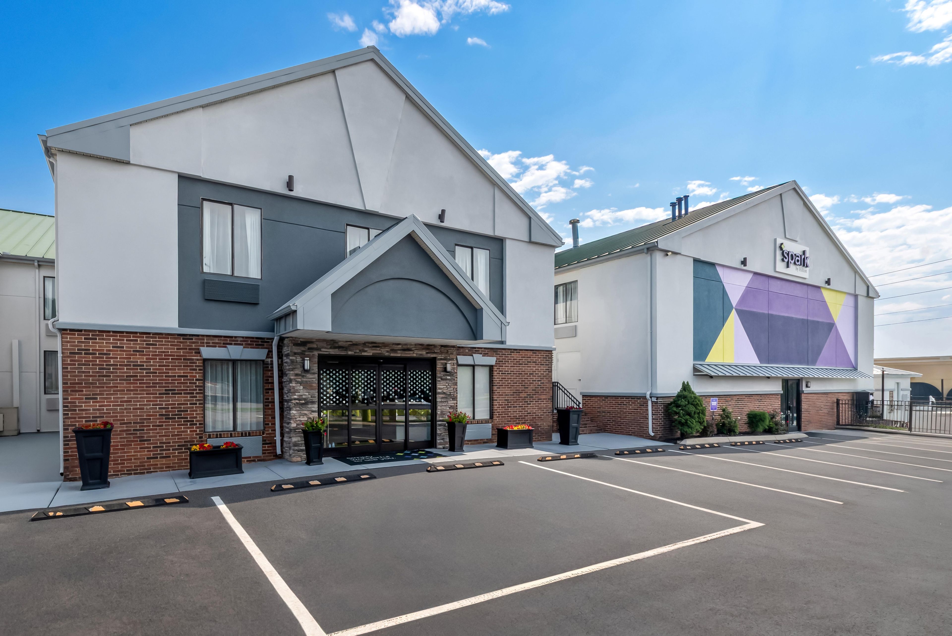 A hotel with a modern design, featuring a parking lot and a large sign on the side.
