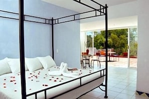 A modern bedroom with a four-poster bed, a glass door leading to an outdoor patio area. - Casa de la Condesa (Mexico City)