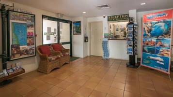 A reception area with wicker chairs, a reception desk, and a poster advertising a cruise.