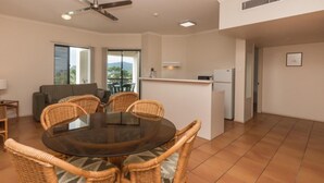 A compact living space with a dining area, kitchenette, and a balcony with a view. - Tropic Towers Apartments (Cairns North)
