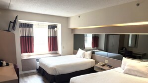 Une chambre d’hôtel avec deux lits, un bureau, une chaise, une armoire et une fenêtre avec des rideaux.