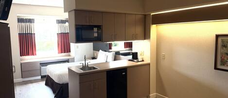 Una kitchenette compacta con pileta, microondas y un pequeño comedor.