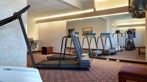 A hotel fitness room with treadmills, a stationary bike, and a mirrored wall.