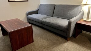 Un canapé gris, une petite table en bois et une lampe posée sur un tapis.