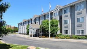 A multi-story hotel with a covered entrance, flagpoles, and a landscaped driveway.
