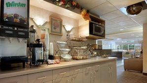 A cafe area with a coffee machine, a microwave, and a display of fruits.