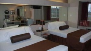 A hotel room with two beds, a desk, a chair, and a large mirror.