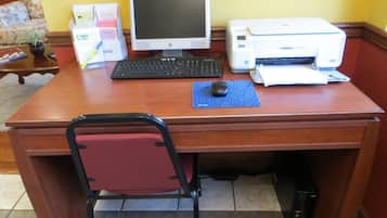 A wooden desk with a desktop computer, keyboard, monitor, and printer.
