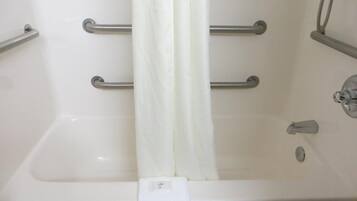 Una bañera blanca con dos barras de apoyo metálicas, una cortina de ducha blanca y una toalla blanca.