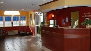 A reception area with a wooden reception desk, a red wall, and a window with blinds.