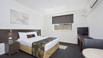 A hotel room with a bed, bedside table, TV, and a window with a view.