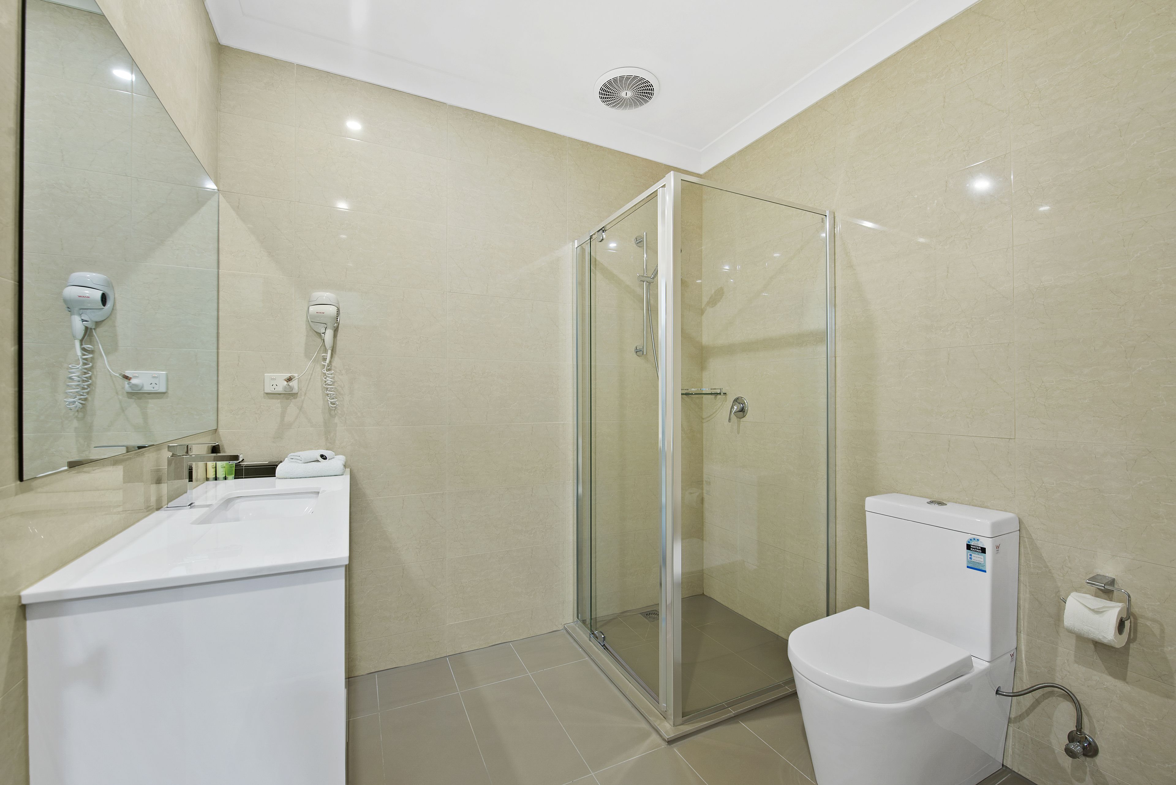 A modern bathroom with a glass-enclosed shower, a white sink, and a toilet.