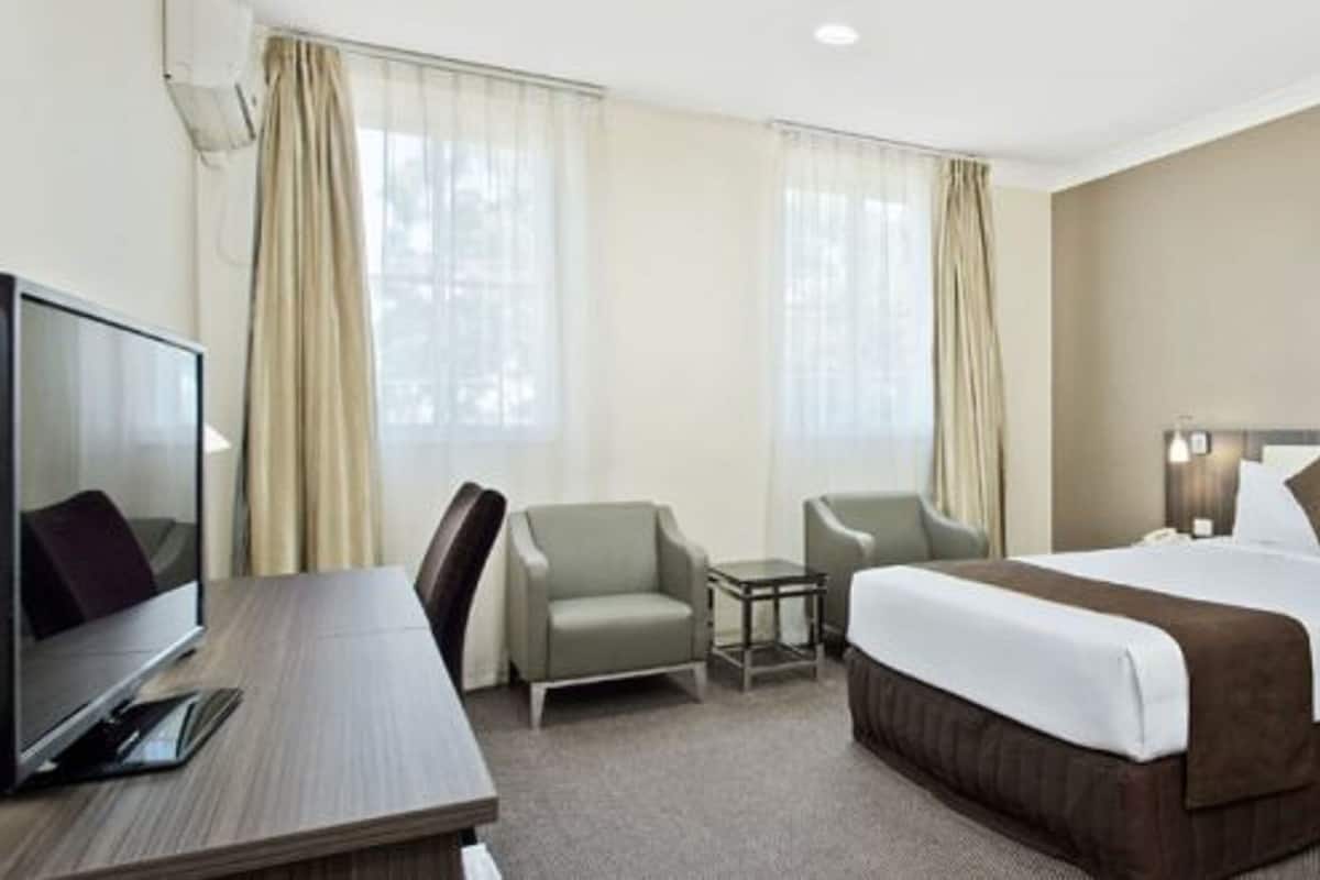 Een hotelkamer met een groot bed, een bureau, een stoel en een televisie.