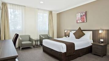 A hotel room with a large bed, a desk, a chair, and a television.
