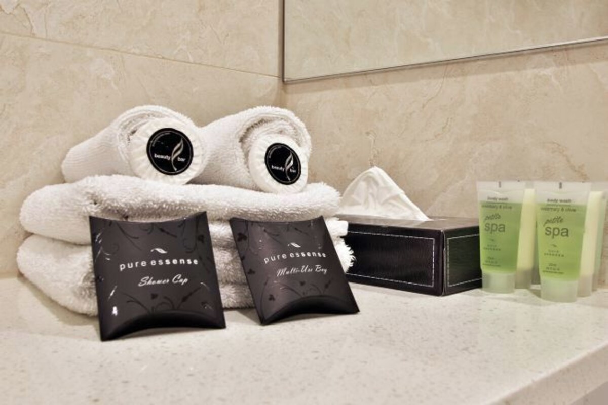 A bathroom with a towel, a bottle of shampoo, and a box of toiletries.