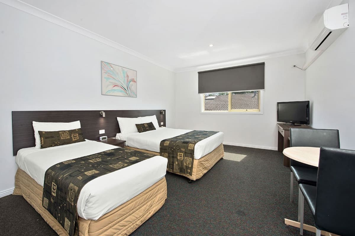 Een hotelkamer met twee bedden, een bureau, een televisie en een raam met uitzicht.