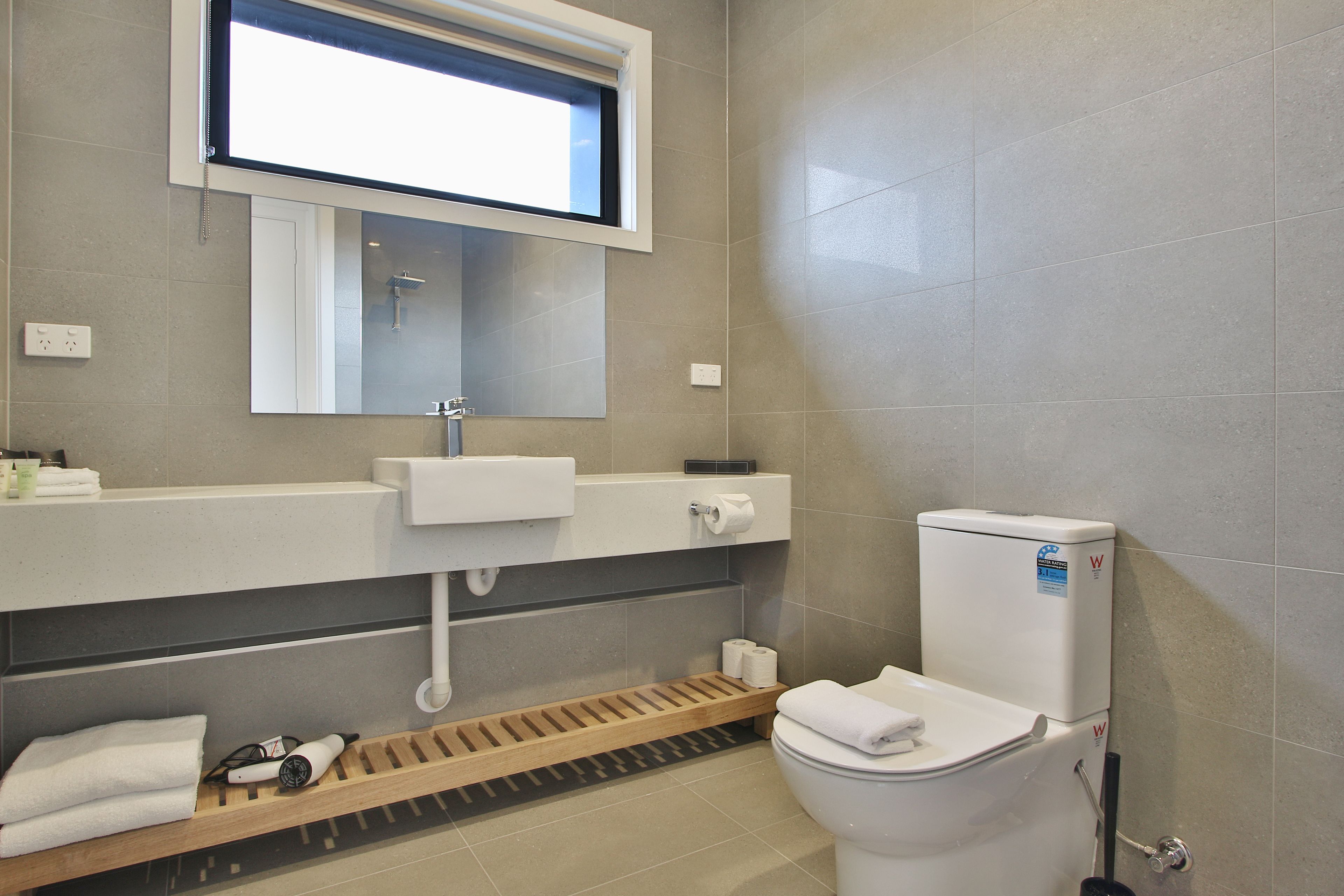 A modern bathroom with a toilet, sink, and shower area.