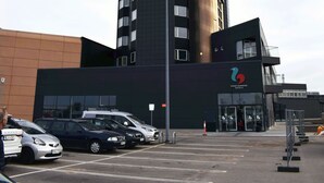 Een hoog hotel met een opvallende, gebogen gevel en een logo aan de zijkant.