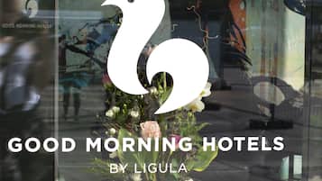 En utställning i ett skyltfönster med en blomsterarrangemang och texten: "GOD MORGON, LIGULAS HOTELL".