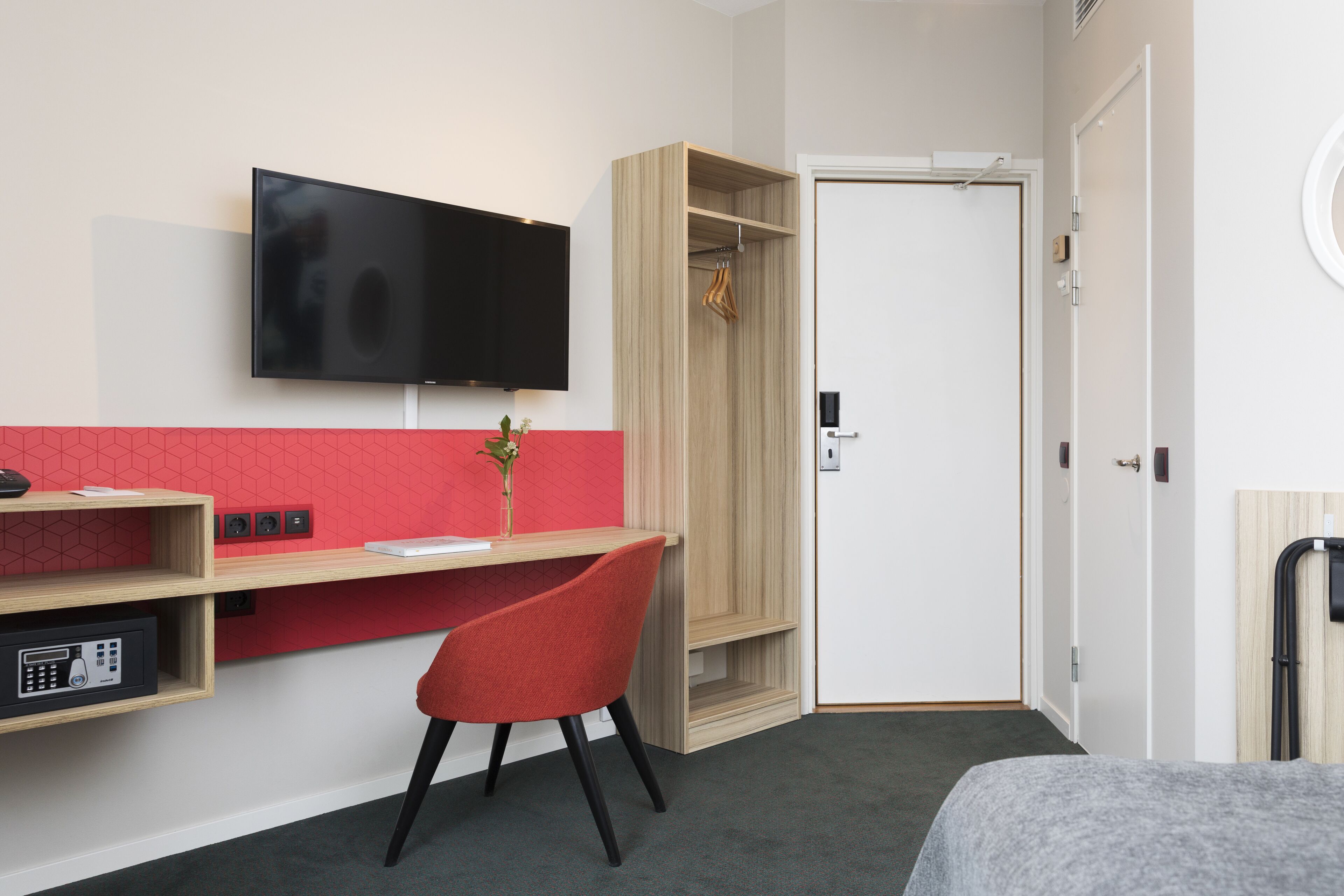 Una habitación de hotel con escritorio, televisión, armario y cama.