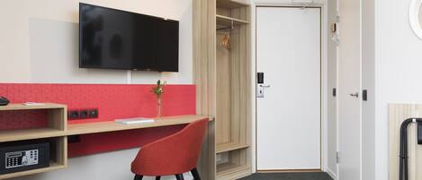 Una habitación de hotel con escritorio, televisión, armario y cama.