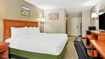 Une chambre d’hôtel avec un grand lit, un bureau avec une chaise, une télévision et un tableau au mur.