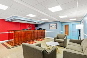 Un hall con mostrador de recepción, zona de estar y una puerta.