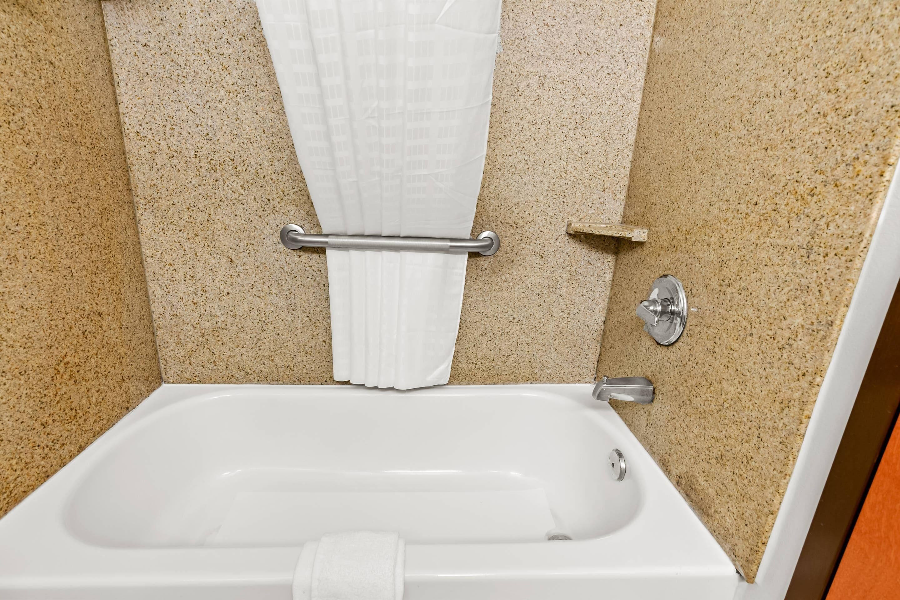 Une salle de bain avec une baignoire, un porte-serviettes et un rideau de douche.