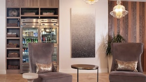 A modern living room with two grey armchairs, a small round table, and a built-in refrigerator stocked with beverages. - Residence Inn Charleston Riverview (Charleston)