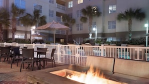 An outdoor seating area with a fire pit, surrounded by palm trees and a pool. - Residence Inn Charleston Riverview (Charleston)