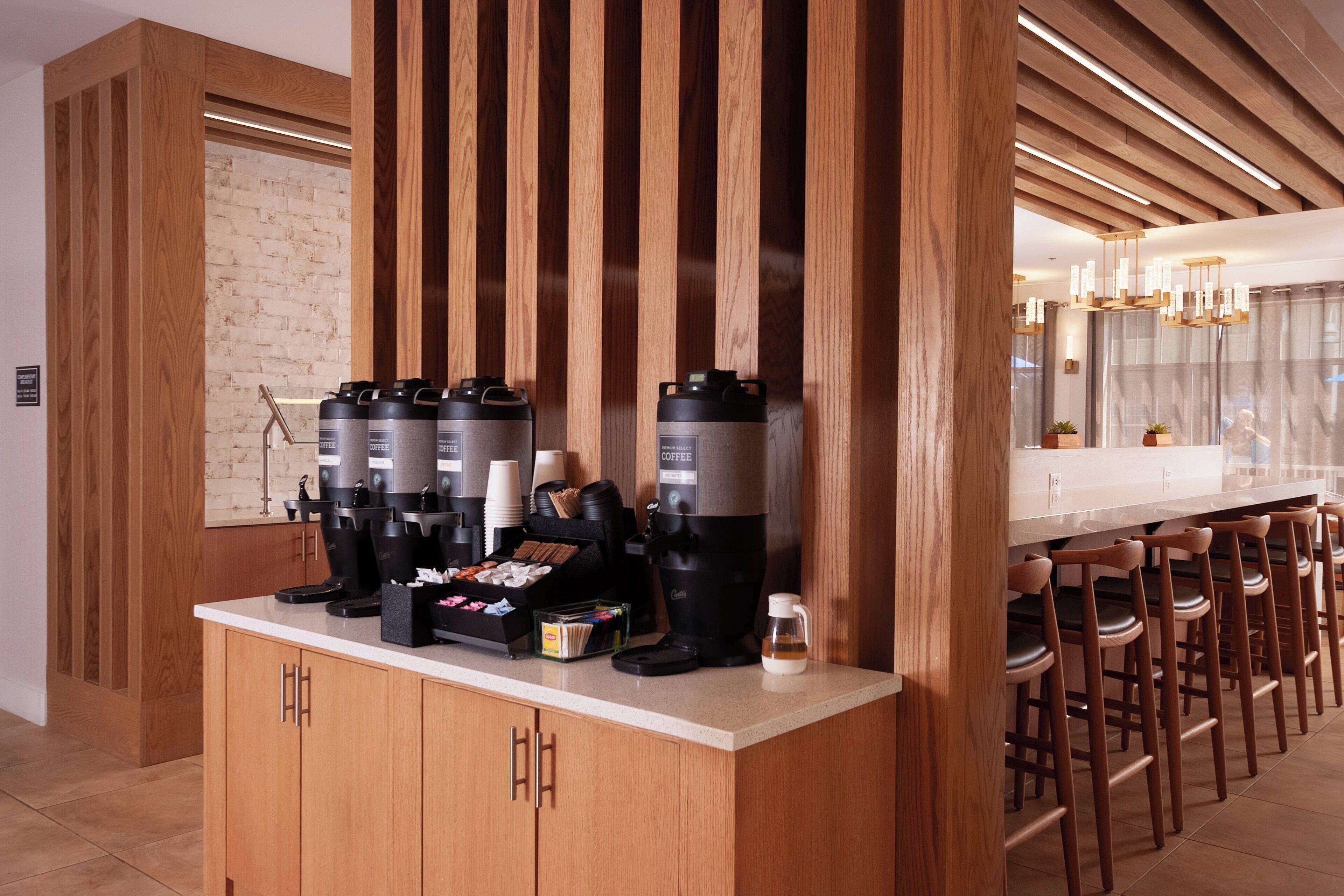 Eine moderne Küche mit einer Kaffeestation, die verschiedene Kaffeemaschinen und eine Auswahl an Kaffeekapseln bietet.