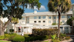 A large, multi-story hotel with a white facade, multiple windows, and a covered outdoor area with a white fence. - Residence Inn Charleston Riverview (Charleston)