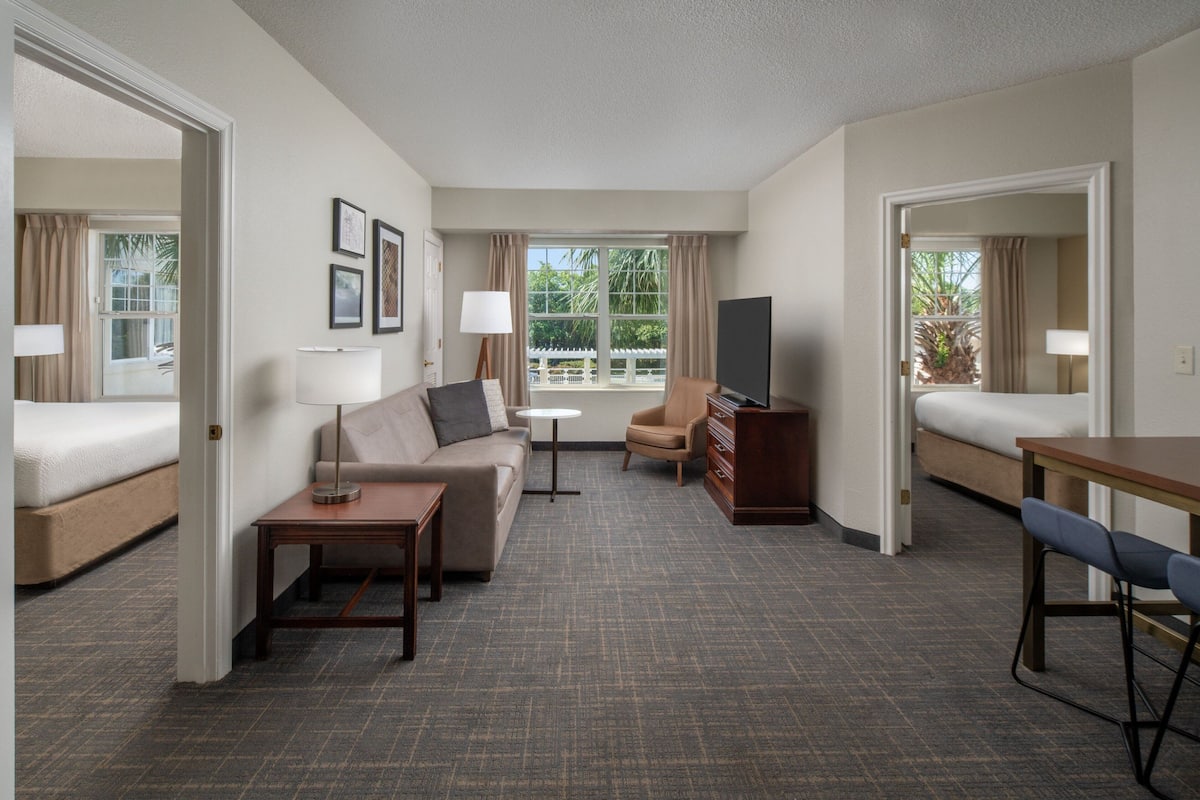 Ein Hotelzimmer mit Bett, Sofa, Fernseher, Schreibtisch und Stuhl.
