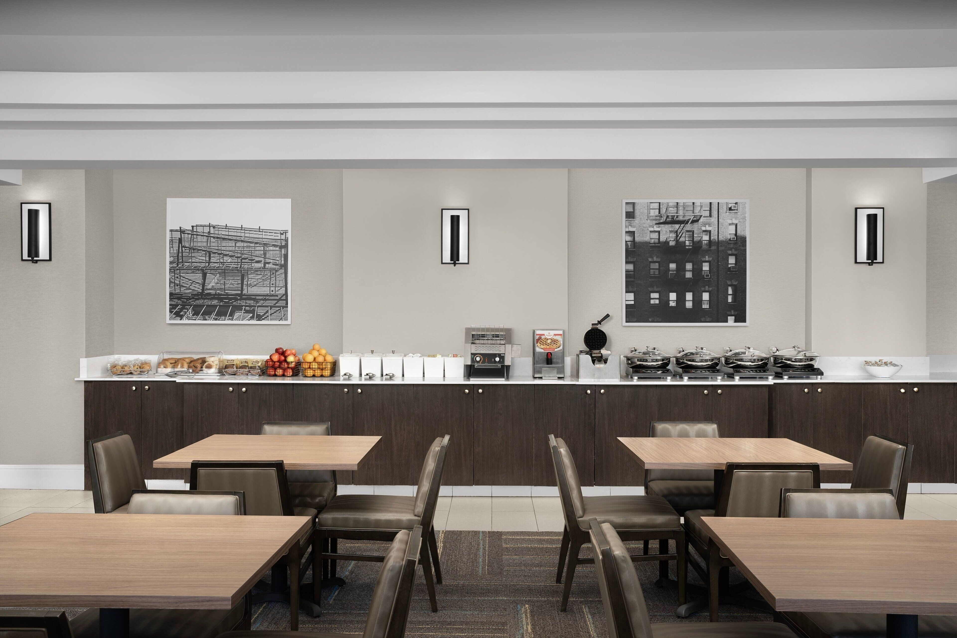 A modern dining area with a long counter, multiple seating options, and artwork on the walls.