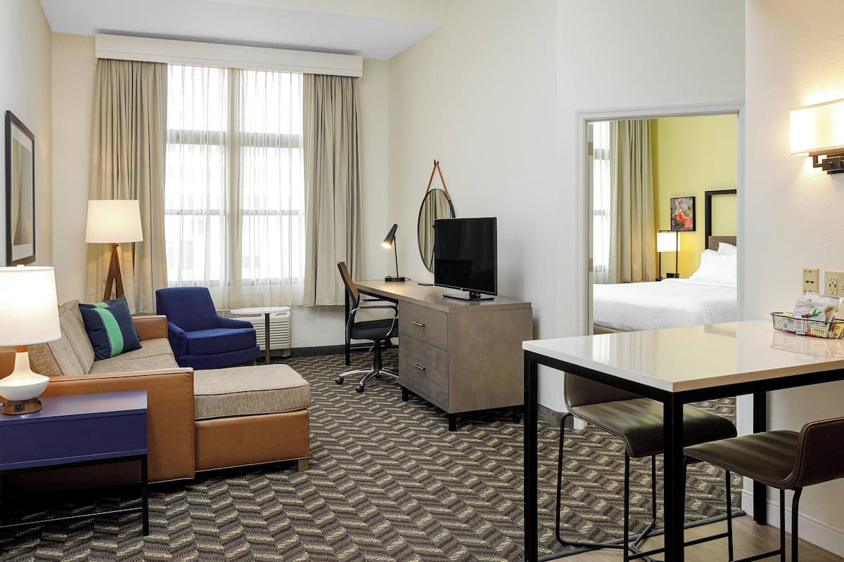 A hotel room with a sofa, armchair, desk, and a bed.