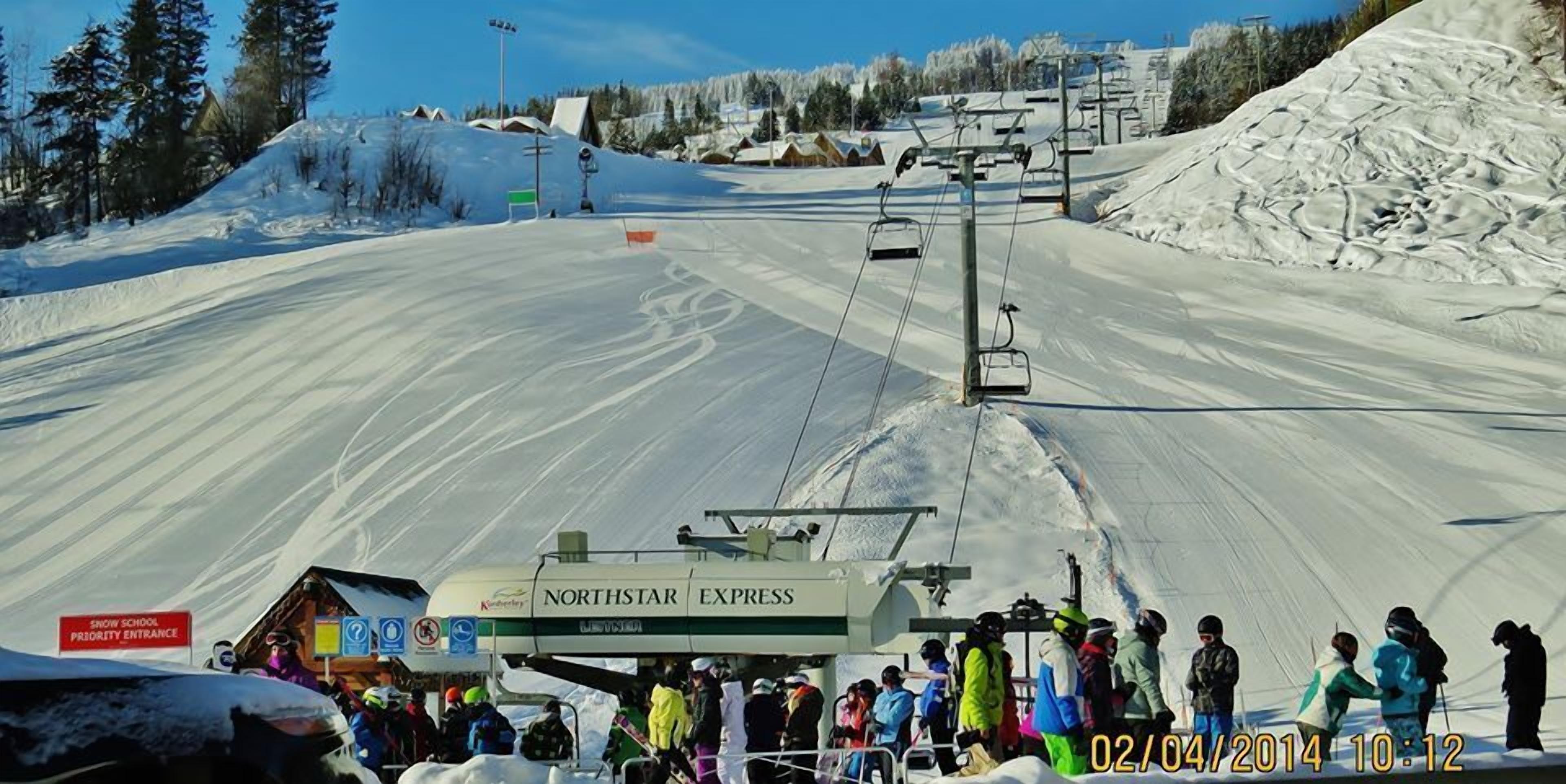 A snow school priority entrance with a ski lift and people waiting.