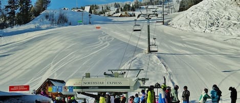 A snow school priority entrance with a ski lift and people waiting.