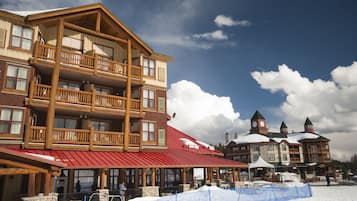 Un amplio refugio de madera con varios balcones y un techo rojo, rodeado de nieve.