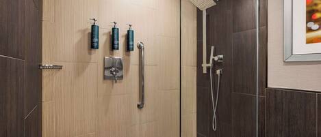 A modern shower area with a wooden panel wall, a glass door, and a framed picture on the wall.