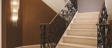 A staircase with ornate black railings and a wall-mounted light fixture.